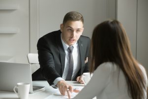 Young woman in a job interview with aggressive man.