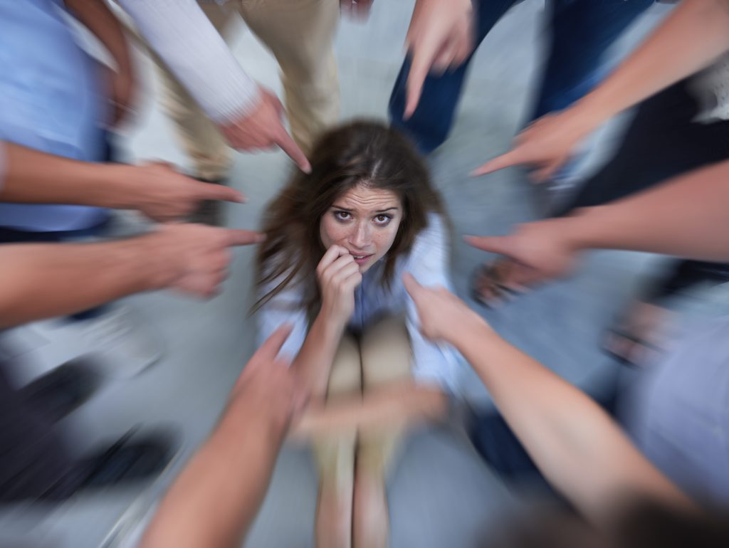 Crumpling under the pressure. a fearful young woman trying to hide from her coworkers bullying her
