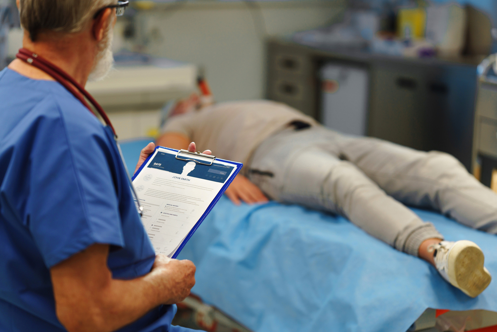 Male patient at an annual physical on the exam table while doctor is looking at the chart